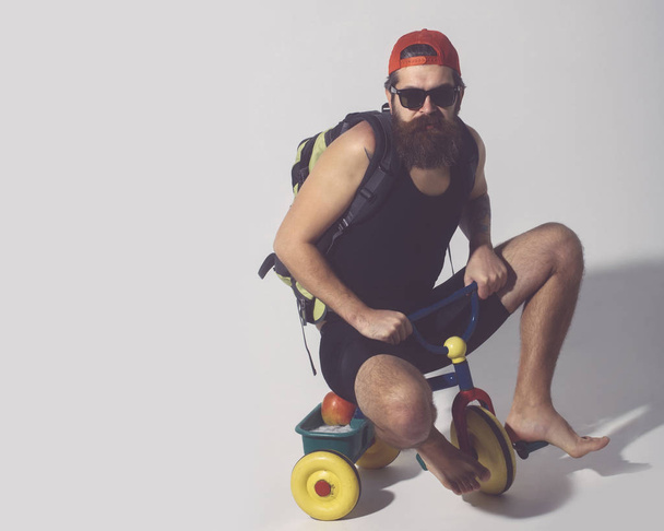 bearded serious man with bag, apple on bicycle toy - Φωτογραφία, εικόνα