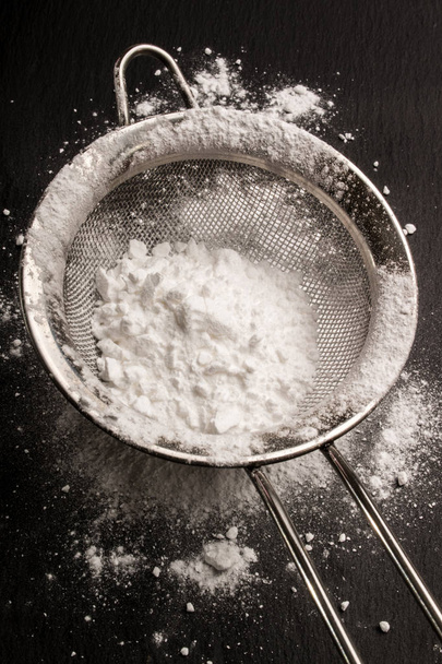 powdered sugar on a metal sieve and on slate  - Fotoğraf, Görsel