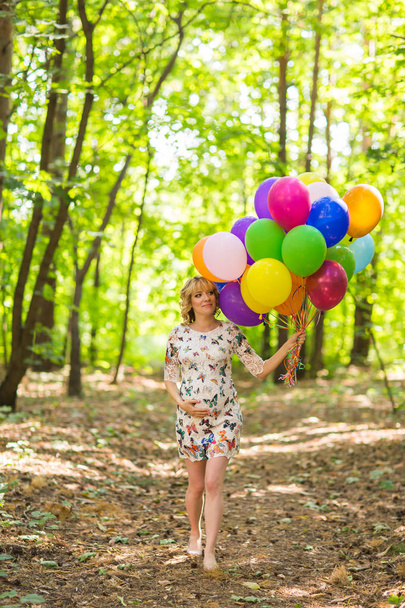 Mladá těhotná žena držící barevné balónky venku - Fotografie, Obrázek