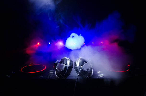 DJ dreht, mischt und kratzt in einem Nachtclub, Hände von DJ zwicken verschiedene Track-Controller auf dem DJ-Deck, Blitzlicht und Nebel, selektive Fokussierung, Nahaufnahme. dj musik club life konzept - Foto, Bild