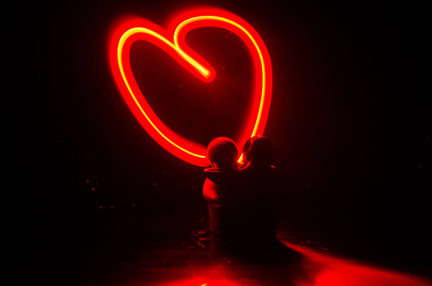 Dwóch młodych kochanków malowania serce w ogniu. Sylwetka para i miłości słów na ciemnym tle - Zdjęcie, obraz