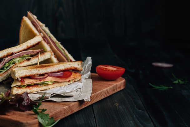 Fresh delicious club sandwich on the wooden dark table with copy space - Fotoğraf, Görsel