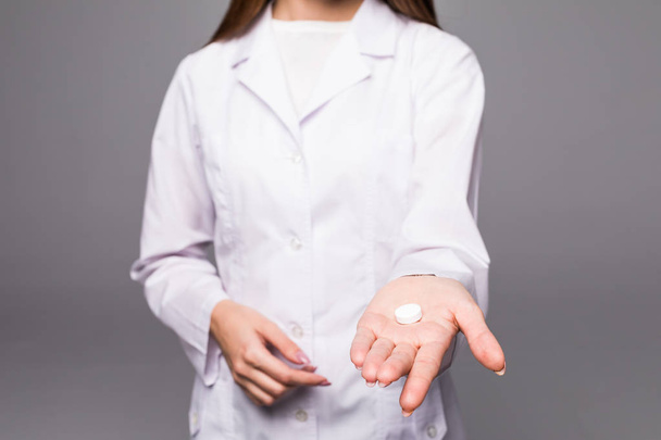 Vrouw verpleegkundige pillen in de hand houden en opdagen duimen geïsoleerd - Foto, afbeelding