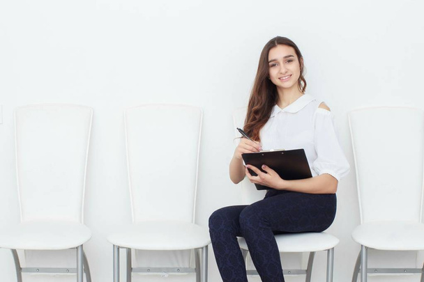 The girl sits on a chair and fills up the documents - Photo, Image