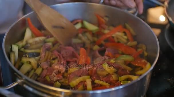 Επικεφαλής μάγειρας τηγανίσματος λαχανικά και το κρέας στο τηγάνι - Πλάνα, βίντεο
