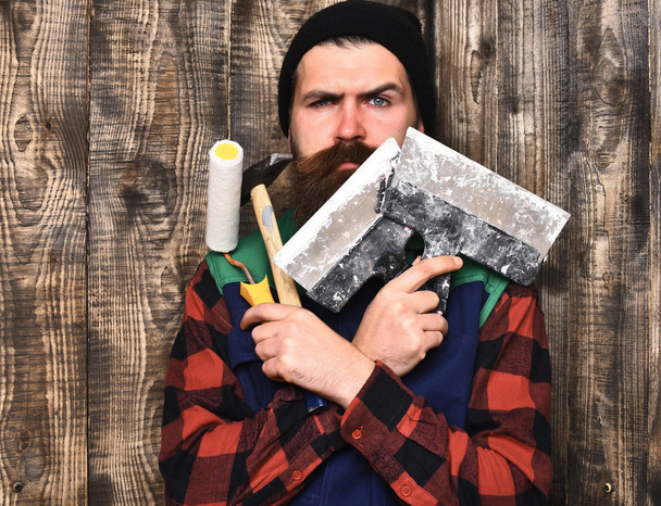 bearded builder man holding various building tools with serious face - Valokuva, kuva