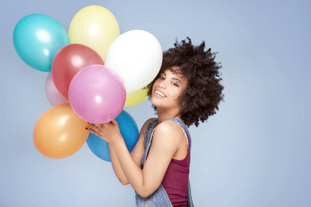 Happy young girl with afro holding balloons. - Photo, image