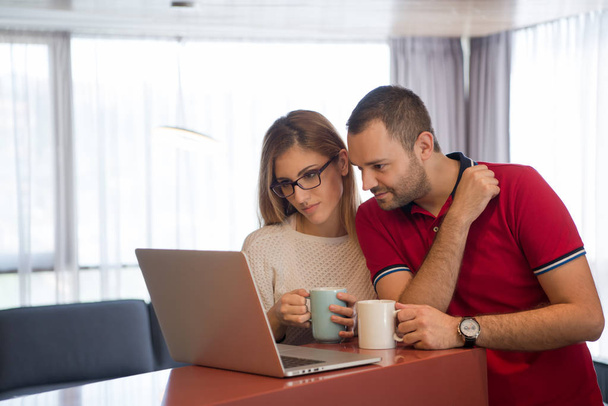 couple drinking coffee and using laptop at home - Photo, image