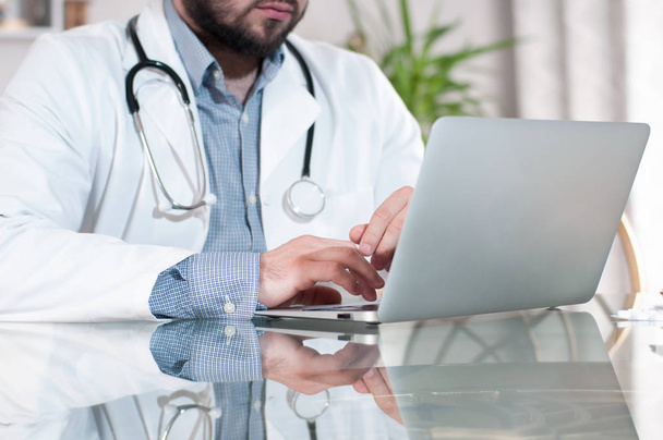 Doctor working on desk with laptop computer - Photo, Image