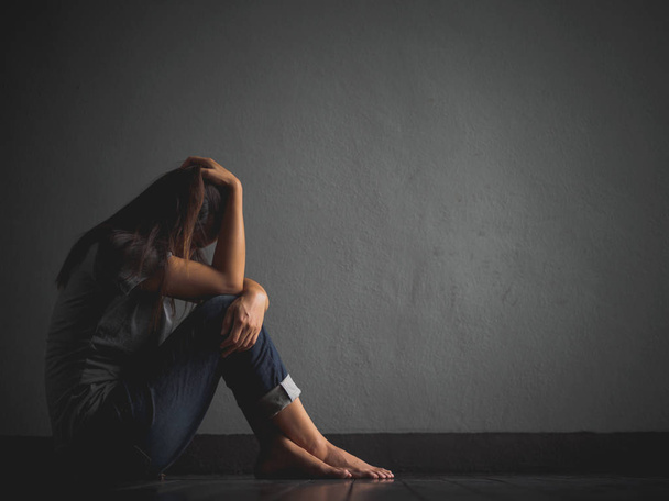 грустная женщина обнимает колено и плачет. Грустная женщина сидит одна в пустой комнате
. - Фото, изображение