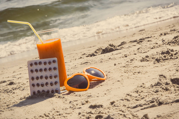 Medical pills, carrot juice and sunglasses at beach, concept of vitamin A and beautiful, lasting tan - Foto, Bild