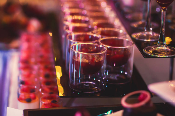 Beautiful line of different coloured cocktails on a open air party, tequila, martini, vodka, and others on decorated catering bouquet table on open air party - Φωτογραφία, εικόνα