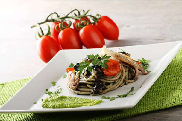 Espaguetis con sepia negra, perejil y tomates cherry
 - Foto, Imagen