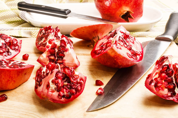 sliced pomegranate with knife on a wooden board - Foto, afbeelding