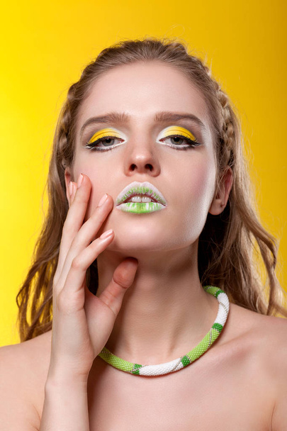 Retrato de uma jovem com maquiagem criativa em umas costas amarelas
 - Foto, Imagem