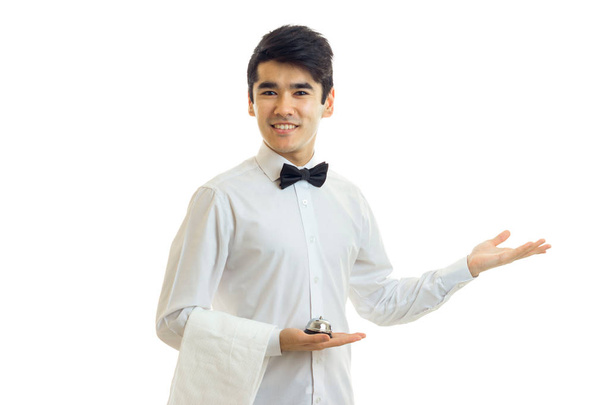 όμορφος νεαρός σερβιτόρος επεκτείνεται το χέρι στο πλάι και χαμογελαστός - Φωτογραφία, εικόνα