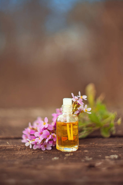 Essential oil of Arabis flower on a table in beautiful bottle - Fotó, kép