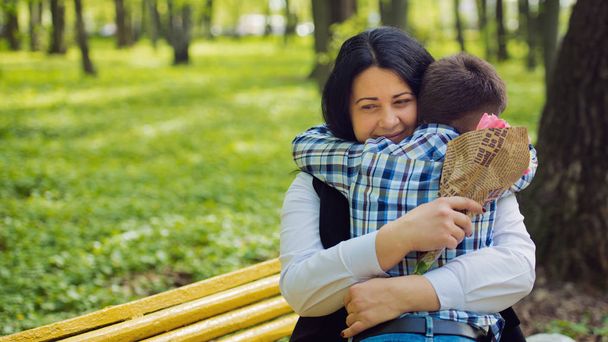 Μικρό χαριτωμένο αγόρι αγκαλιά με τη μαμά της στο πάρκο.  - Φωτογραφία, εικόνα