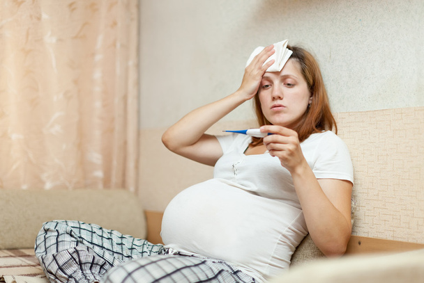 pregnant woman with thermometer in home - Foto, Imagem