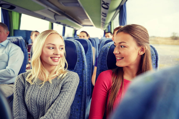 happy young women talking in travel bus - 写真・画像
