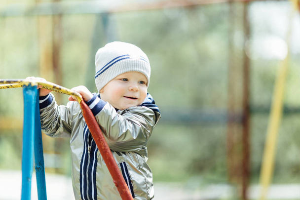 Little boy riding a swing in park playground - 写真・画像