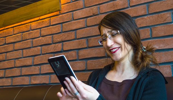 Молодая счастливая женщина с длинными волосами наслаждается своим смартфоном
 - Фото, изображение