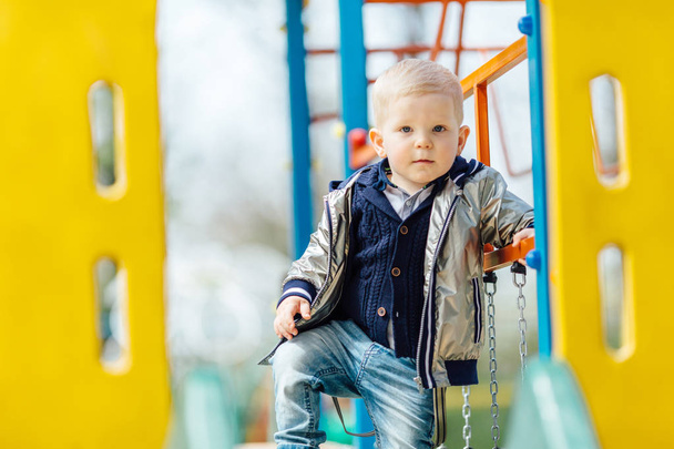 Little boy riding a swing in park playground - Photo, image