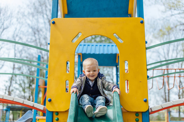 Little boy riding a swing in park playground - Фото, изображение