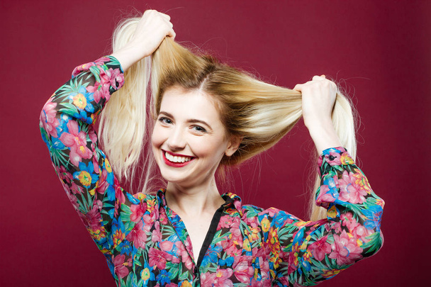 Laughing Girl with Long Hair Wearing Colorful Shirt is Having Fun in Studio. Young Woman with Charming Smile on Pink Background. - Valokuva, kuva
