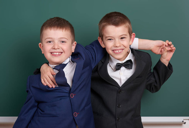 two friends, elementary school boy near blank chalkboard background, dressed in classic black suit, group pupil, education concept - Valokuva, kuva