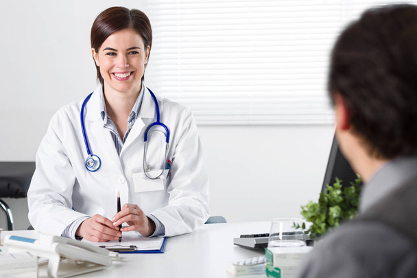 Χαμογελαστός νεαρός γιατρός θηλυκό ακούγοντας ασθενή - Φωτογραφία, εικόνα