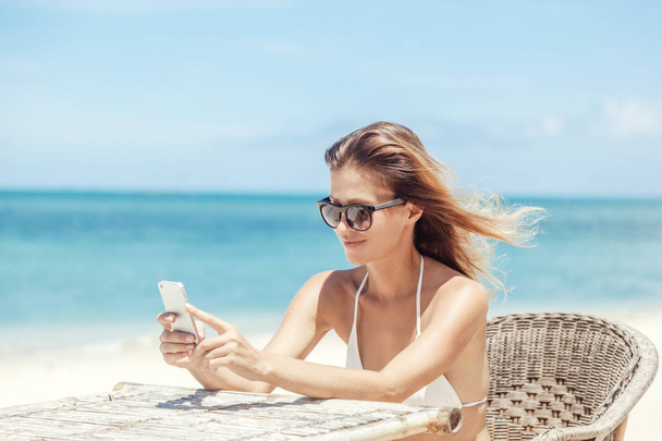 Young beautiful woman with mobile phone on the shore of the trop - Foto, Imagen