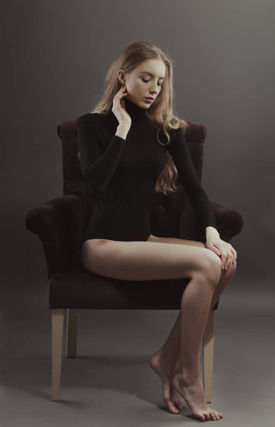 Привлекательная молодая модель позирует для модельных тестов, сидя на стуле
 - Фото, изображение
