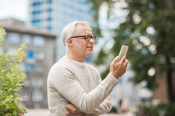 senior man texting message on smartphone in city - Foto, afbeelding