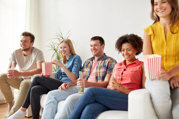 счастливые друзья с кукурузой, смотрящие телевизор дома
 - Фото, изображение