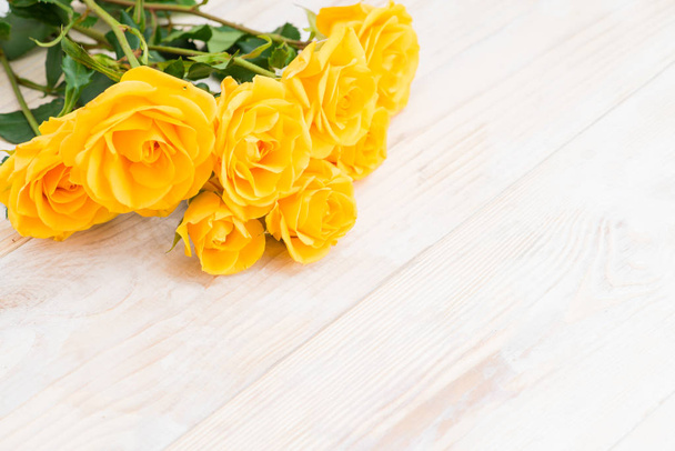 yellow shrub rose on a white wooden table, the pattern for your  - Foto, afbeelding