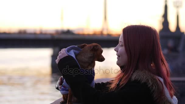 Teen girl with a little dog on a night street near river. - Séquence, vidéo