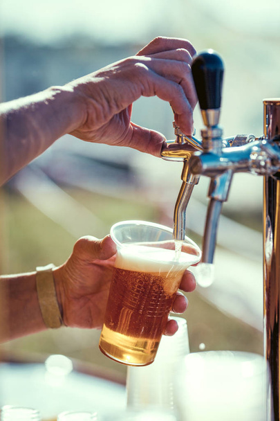 barman hand at beer tap pouring a draught lager beer - 写真・画像