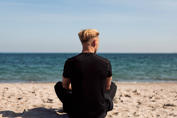 hombre sentado en la playa en un día soleado
 - Foto, imagen