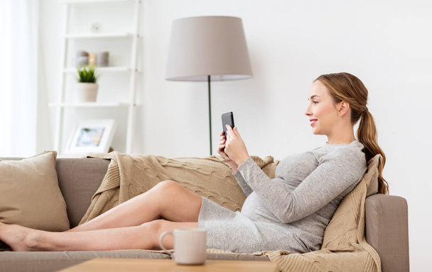 happy pregnant woman with tablet pc at home - Foto, afbeelding