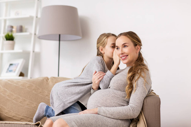 happy pregnant woman and girl gossiping at home - Photo, image