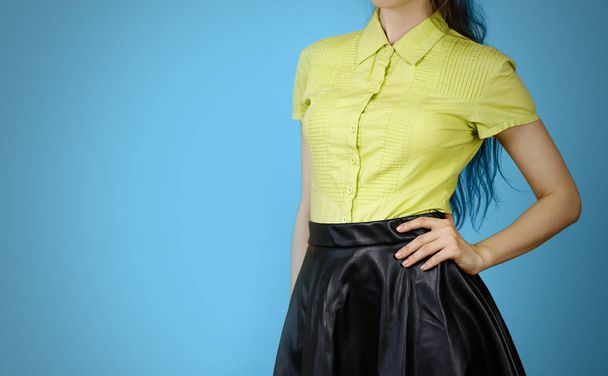 The girl in the yellow shirt and leather skirt. Isolated on blue - Foto, afbeelding