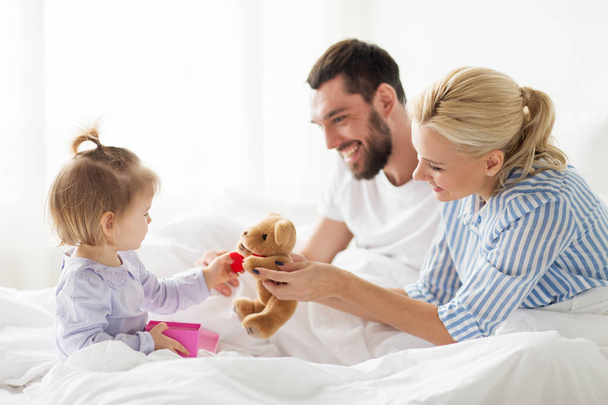 happy family with gift box in bed at home - Φωτογραφία, εικόνα