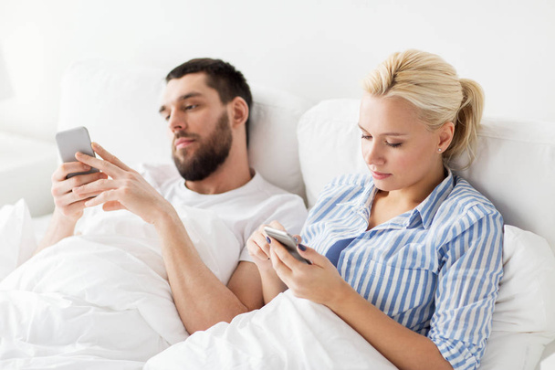 couple with smartphones in bed at home - Φωτογραφία, εικόνα