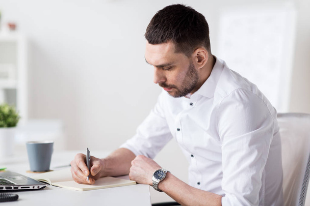 businessman writing to notebook at office - Zdjęcie, obraz