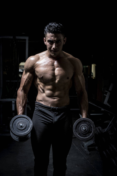 Young man exercising in dark and old gym - Valokuva, kuva
