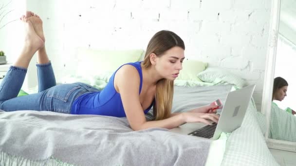 Young woman making online shopping with her credit card in her bed - Πλάνα, βίντεο
