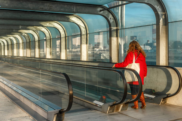 Жінка з червоною курткою на ескалаторах, поза великим містом
 - Фото, зображення