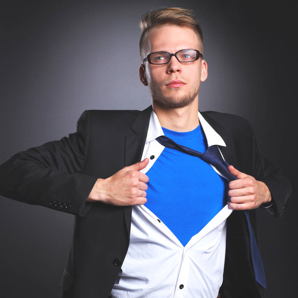 Jonge zakenman gedraagt zich als een super held en scheuren zijn overhemd, staande - Foto, afbeelding