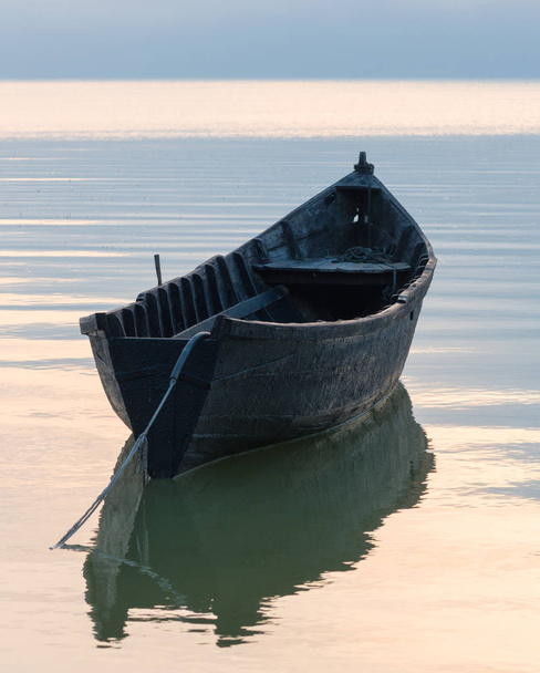 夕暮れ時の湖の古い手漕ぎボート - 写真・画像